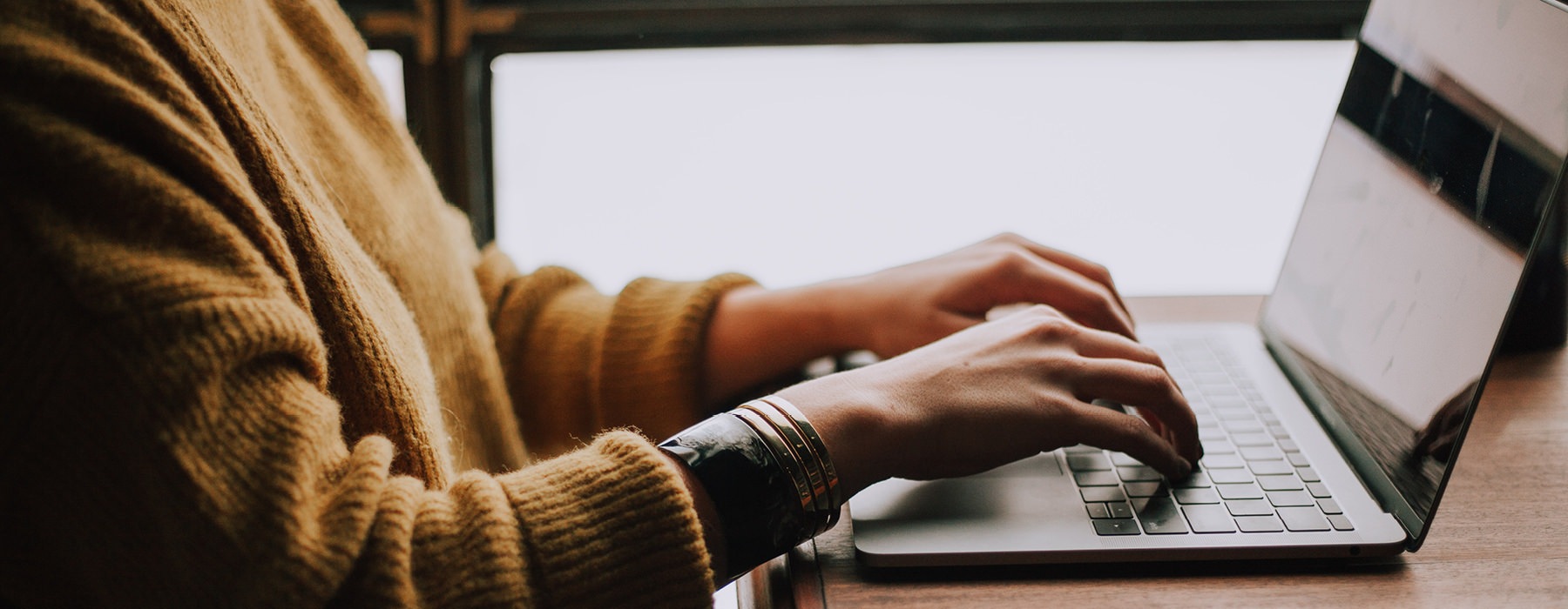 woman sits at her desk and works on laptop